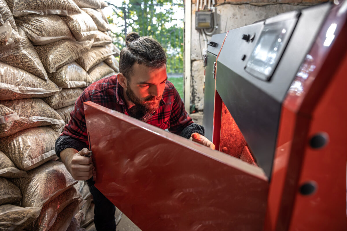 the young man looking into a solid fuel boiler working with biofuels economical heating